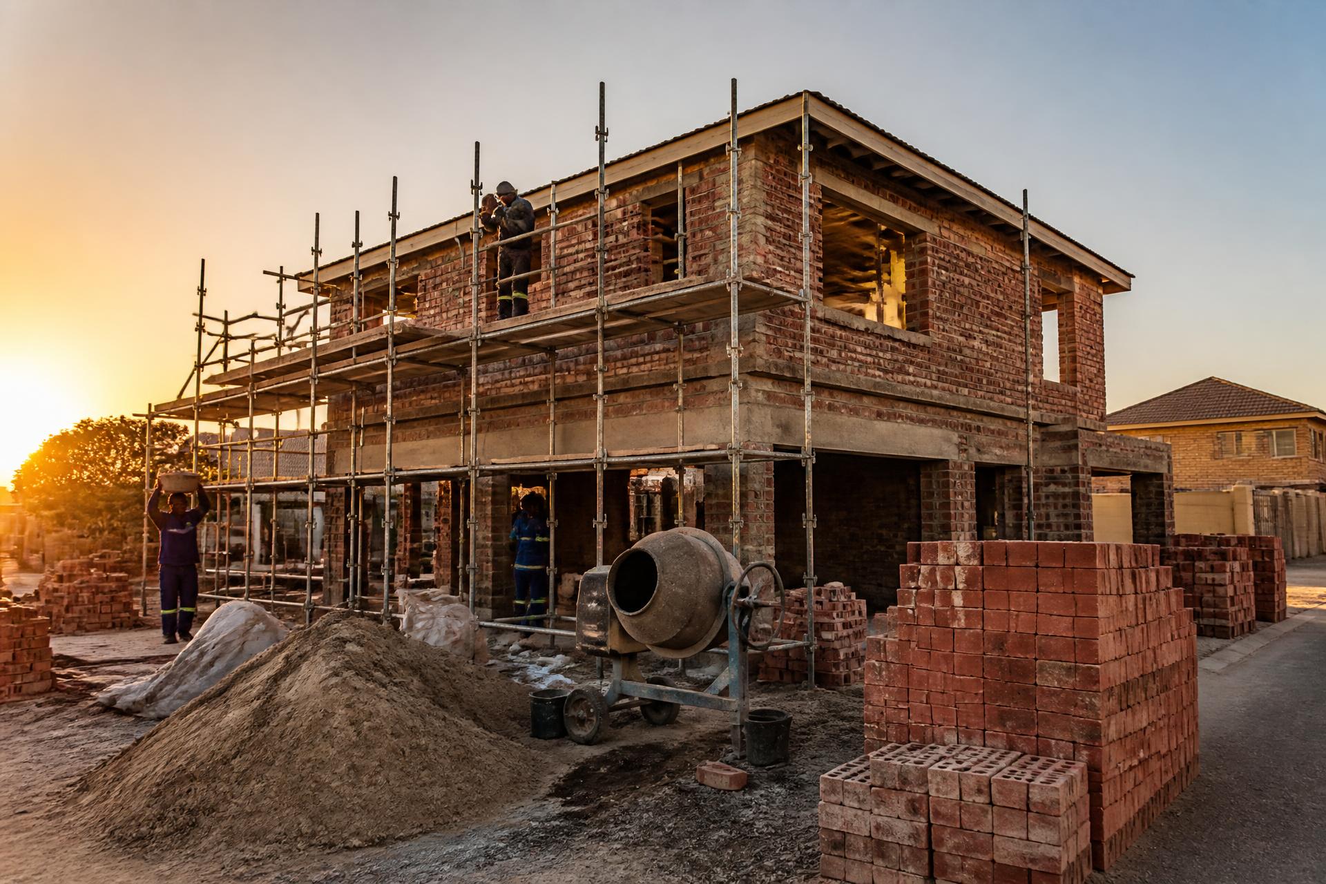 Christie Construction team building a double-storey face brick house at sunset